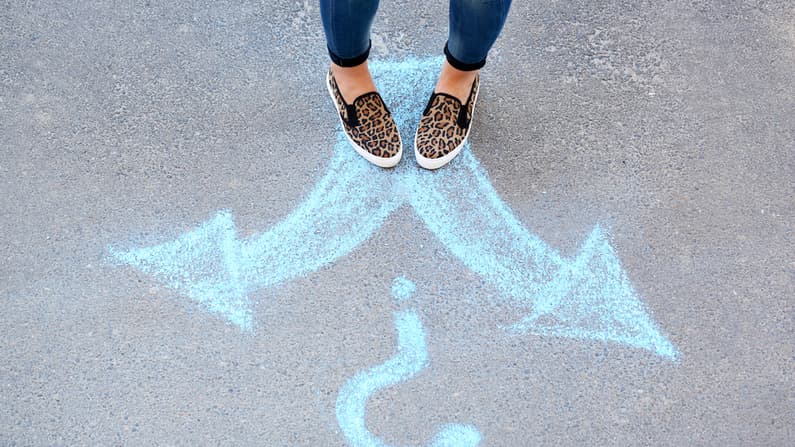 Woman looking at two arrows on pavement